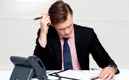 Stressed business man writing at his desk